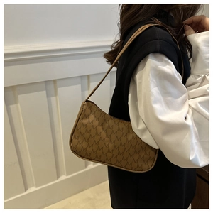 Side view of a brown monogram crescent shoulder bag worn on a minimalist white background