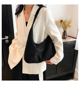 Borsa a spalla nera a mezzaluna opaca indossata con un elegante blazer bianco