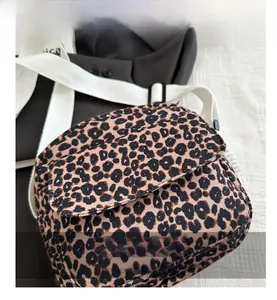 Detail view of leopard print mini crossbody bag with textured fabric and white wide strap