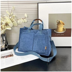 Detail of blue corduroy tote bag with front pockets and adjustable fabric shoulder strap