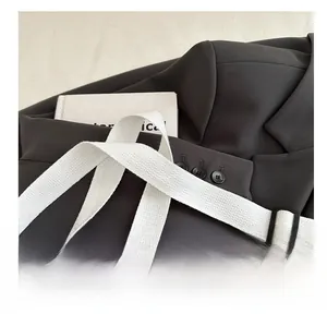 Detail of adjustable woven shoulder strap with black buckle and fabric sleeve texture