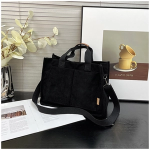 Detail of black corduroy tote bag showing front pockets and detachable shoulder strap