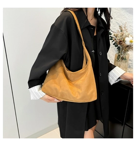 Dettaglio della borsa hobo in pelle scamosciata marrone con texture morbida e drappeggio