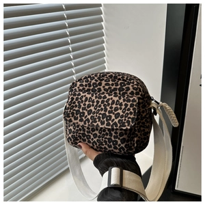Detail of leopard print crossbody bag featuring a wide fabric strap and adjustable buckle