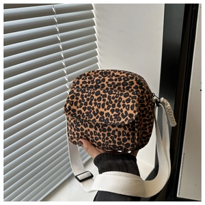 Close-up of leopard print canvas crossbody bag with white wide strap and zipper detail