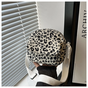 Detailed close-up of leopard print canvas bag with wide white strap and zip closure