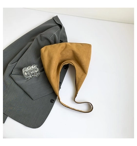 Dettaglio della borsa a mezzaluna in camoscio giallo senape con tracolla minimalista