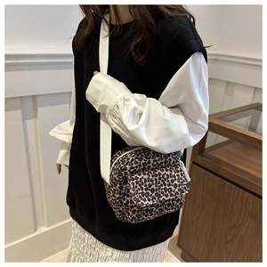 Lifestyle view of a trendy leopard print crossbody bag with white fabric strap