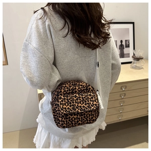 Rear view of a leopard print crossbody bag with white strap in a cozy interior setting