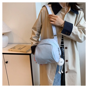 Detail of light blue nylon crossbody bag with zipper and plush monster charm