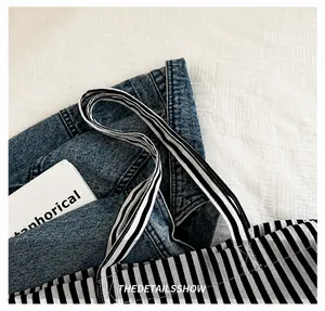 Détail de la bandoulière du sac en toile rayée montrant la texture durable