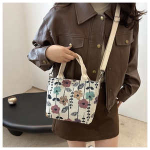 Detail of floral corduroy tote bag with adjustable strap worn by model in warm indoor setting