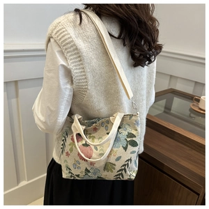 Detail view of a floral tapestry tote bag with woven texture and a crossbody strap