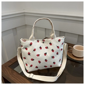Detail of white corduroy bucket bag with strawberry embroidery and adjustable strap