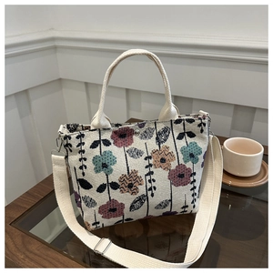 Detail of cream woven tote bag with colorful floral embroidery and adjustable strap