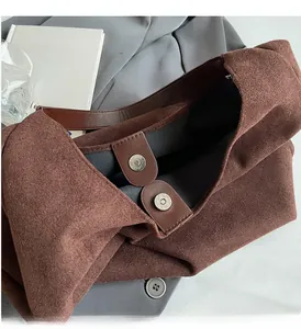 Close-up of matte brown tote bag showing the magnetic buckle and polished metal hardware