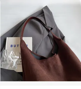 Detail of dark brown suede tote bag with durable leather handles on gray blazer