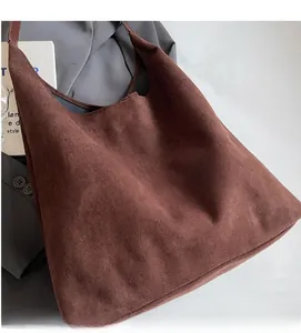 Detailed view of brown suede tote bag placed on a grey blazer for a minimalist style
