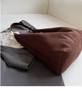 Detail of soft dark brown suede tote bag with leather strap on stylish grey blazer