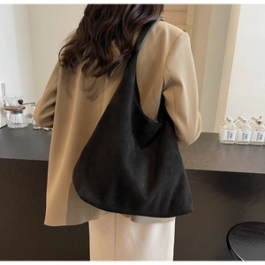Detail of a large black suede hobo bag with a wide shoulder strap in a minimalist style