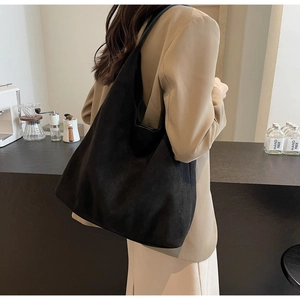Detailed view of large black tote bag with matte texture on a female model