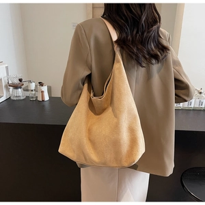 Detailed shoulder view of a large sand-colored suede tote bag with minimalist crescent design