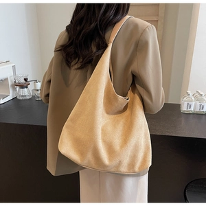 Minimalist camel suede tote bag shown in a stylish shoulder carrying view with modern cafe backdrop
