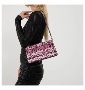 Sac sous le bras imprimé léopard rose porté avec plaque logo métallique chic
