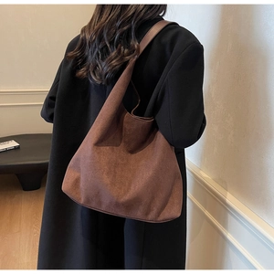 Close-up of brown suede tote bag with wide strap on shoulder for autumn commute