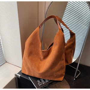 Detailed view of the brown suede tote bag featuring a wide leather strap and soft texture