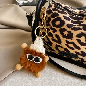 Detail of furry monster bag charm with knit hat and glasses on leopard print handbag
