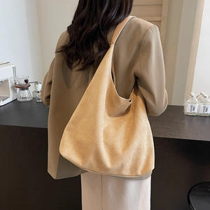 Minimalist khaki large capacity tote bag shown from back view on model in a cozy cafe
