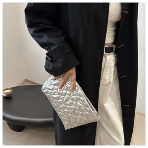 Detail van zilveren gewatteerde clutch met metallic textuur en ruitpatroon