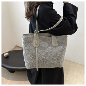 Détail du sac cabas en fausse fourrure grise avec anses en cuir sur l'épaule du modèle