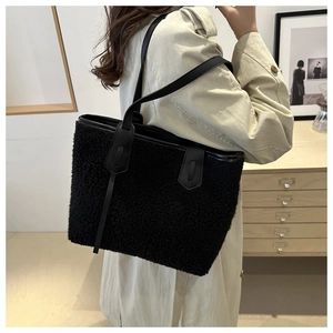 Détail d'un cabas noir en polaire avec des lanières en cuir pour un style d'automne