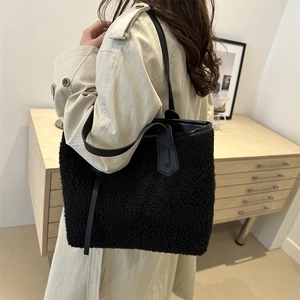 Grande borsa tote nera in peluche indossata con trench beige per la moda autunno-inverno