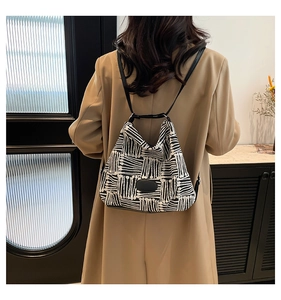 Detailed back view of a minimalist black and white geometric canvas tote bag on a model