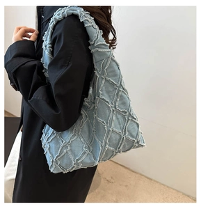 Detail der distressed Denim-Struktur und gestepptem Karomuster der blauen Tragetasche