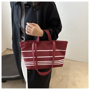 Detail der weinroten Canvas-Tasche mit weißen Streifen, kombiniert mit schwarzem Mantel