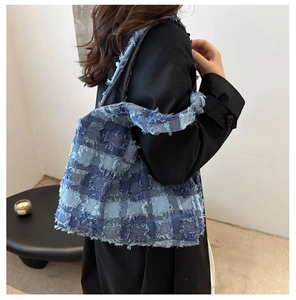 Detail der blauen Denim-Patchwork-Tragetasche mit ausgefransten Fransen am Modell