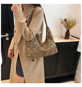 Borsa hobo alla moda con stampa leopardata indossata con un trench beige in uno studio