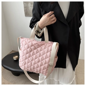 Detail of pink quilted tote bag with cream straps and adjustable shoulder strap for women