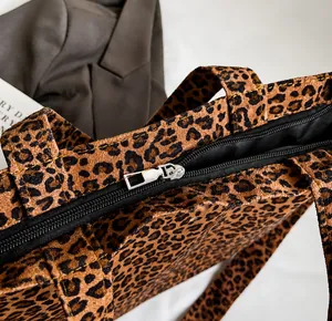 Detailed macro view of a smooth silver metal zipper on a leopard print canvas tote bag