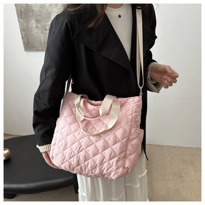 Detailed view of pink quilted tote bag with side pocket and cream woven handles