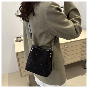 Détail d'un sac seau noir avec strass et bandoulière rayée porté par un mannequin