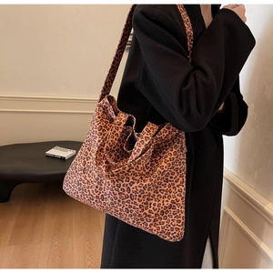 Detail of large leopard print tote bag with wide shoulder strap worn with black coat