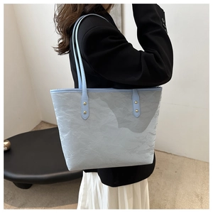 Detailed macro of a light blue tote bag with unique pleated texture and gold rivets