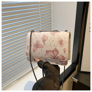 Détail du sac bandoulière avec motifs papillon et étoile et chaîne en métal noir