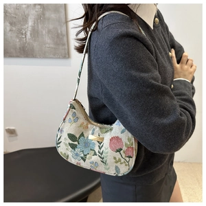 Close-up of floral jacquard fabric texture and gold metal logo plate on hobo bag