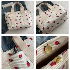 Detail view of corduroy bucket bag showing strawberry print and magnetic snap closure